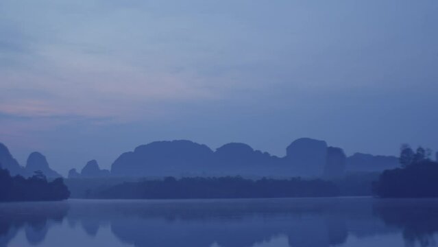 .Beautiful blue atmosphere in twilight at the swamp..Steam floats on the surface of the water with the reflection of the forest..Landscape with the image of lake Nong Thale Krabi.