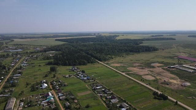 Aerial landscape of green trees and meadows among small houses in Nema