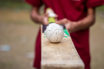 A boy is holding a ball with a bat and the background blurred