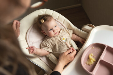 the first baby feeding. Mom feeds the baby with a spoon. Motherhood, child care