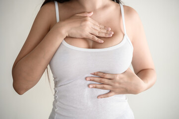 Young Asian woman pressing touching her chest for checking lady breast cancer symptom diagnosis...