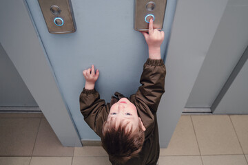 A small child presses the elevator call button. Baby reaches for the elevator button in a...