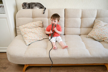 Baby dangerously plays with hair curling tongs, risking burns or injuries. Parents should keep a watchful eye on their little one to prevent accidents. Kid aged about two years (one year ten months).