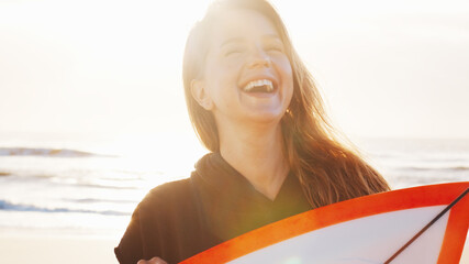 Obraz premium Woman surfer stands with surfing board on the tropical beach and laughs