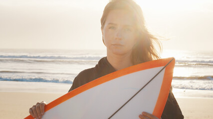 Woman surfer stands with surfing board on the tropical beach. Portrait of arrogant female surfer