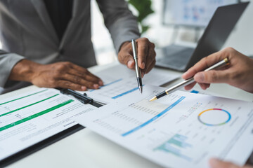 A group of business analysts discuss the summary graph report on business expenses and work information about the company's financial statements.