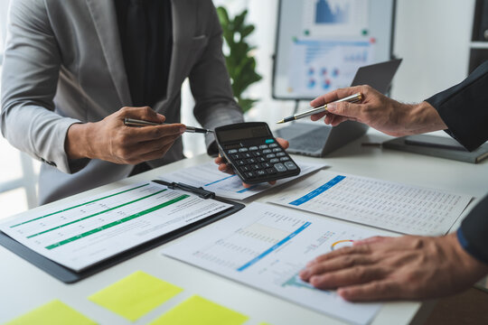 Businessman using calculator to calculate company financial statements with colleagues have an analysis Discuss documents and work together to solve problems within the company.