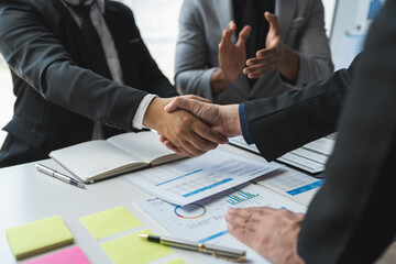 Team of businessmen, investors congratulate their teammates for successful performance in finance, stocks, marketing in a stand out with shaking hands in modern office.