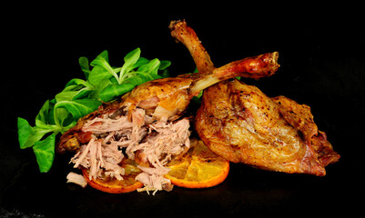 Two roasted duck legs with orange and lambs leaf lettuce garnish