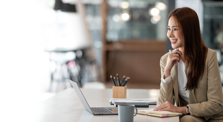Image of young beautiful joyful businesswoman smiling while working with laptop in office, copy space.