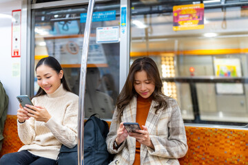 Asian woman using mobile phone text online message or searching data during travel on subway...