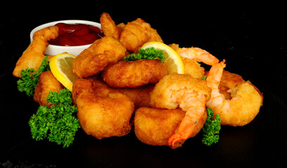 Crispy battered prawns with lemon, slices and parsley herb garnish and tomato sauce dip