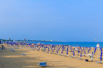 sandy beach with umbrellas and blue sea. distant buildings of the city