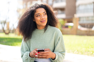 Fototapeta na wymiar Young African American woman at outdoors using mobile phone
