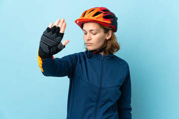 Young cyclist woman isolated on blue background making stop gesture and disappointed