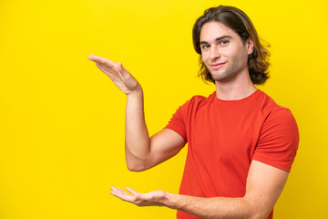 Caucasian handsome man isolated on yellow background holding copyspace to insert an ad