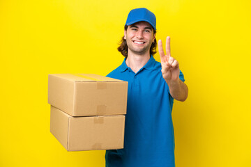 Fototapeta na wymiar Delivery handsome man isolated on yellow background smiling and showing victory sign