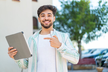 Handsome Arab man holding a tablet at outdoors and pointing it