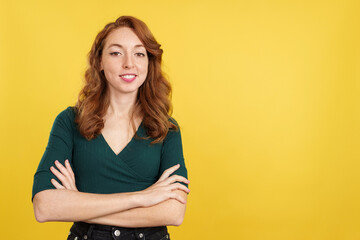 Redheaded woman standing with arms crossed smiling at the camera