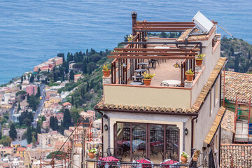 Fototapeta premium Cafe on Saint Antonio Square in Castelmola town on Sicily Island, Taormin city on background, Italy