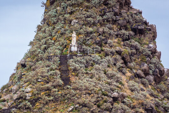 Our lady statue on one of the islets of Cyclopean Isles seen from a shore of Aci Trezza township on Sicily Island, Italy