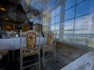 Dining room of a vintage danish seaside hotel seen through the windows with reflections of the outside surroundings