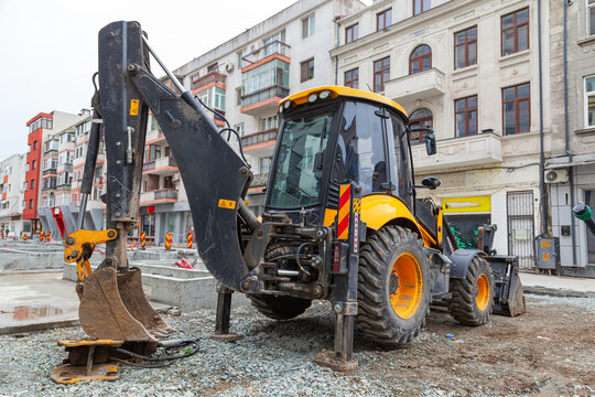 The work of public utilities on the laying of communications in the ground with the help of an earthmoving tractor in the center of the city .