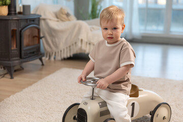 Happy child at home. Little toddler boy driving big vintage toy car and having fun. Smiling kid playing at home. Baby boy playing with toy in living room indoors