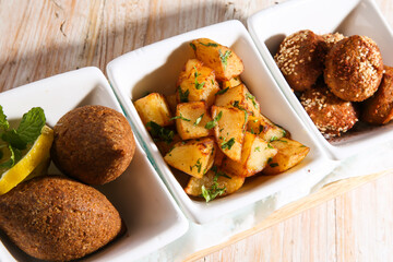 hot mezza with Kebbeh, kibbe, kebbah, kibbeh,Batata Harra or lebanese spicy potatoes and falafel served in dish isolated on background top view of hot mezza