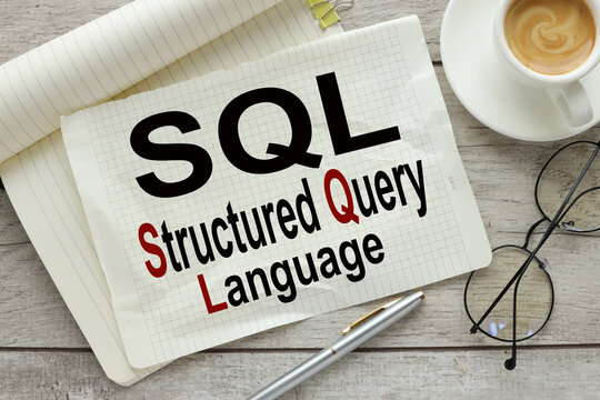 SQL language . large notepad with text near cup of coffee and glasses