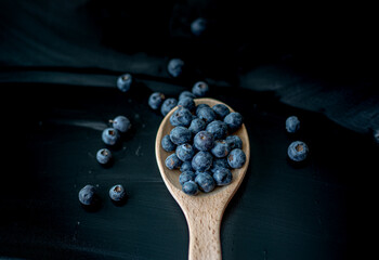 Fresh Blueberries in a wooden spoon on dark background, top view.