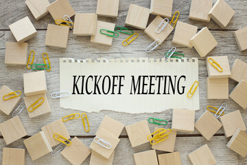 wooden background with many scattered cubes. torn paper with text. Kick-Off Meeting