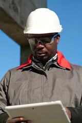 African american worker with tablet computer stands at construction site