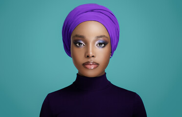 African beautiful girl in a colored headscarf on her head. Blue background.