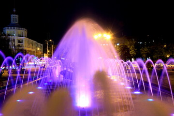 Fototapeta na wymiar Fountain with colorful illumination at night, Creative water design. Ukraine, Dnipro