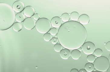 Abstract oil serum and water droplets to create bubbles pattern with pale green gradient ...