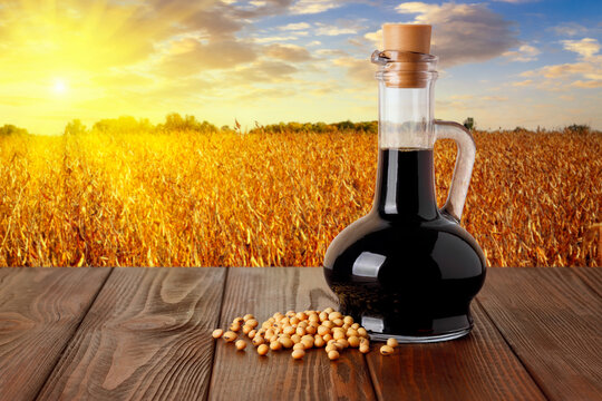 soy sauce in bottle on table and ripe soybean field on sunset as background