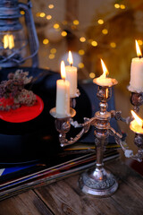 stack of vinyl discs, burning candles in a candlestick, magical objects in a dim room, an atmosphere of magic, the development of imagination, Halloween holiday, cozy musical holiday mood