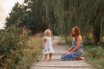 mother and daughter walk on the bridge by the water, girl in a hat on a wooden bridge, walk by the pond, pond, family near the lake   © Ірина Савченко