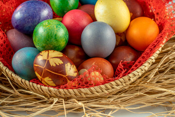 Fototapeta na wymiar Multicolored Easter eggs in a basket over straws. Pastel colored Easter eggs.