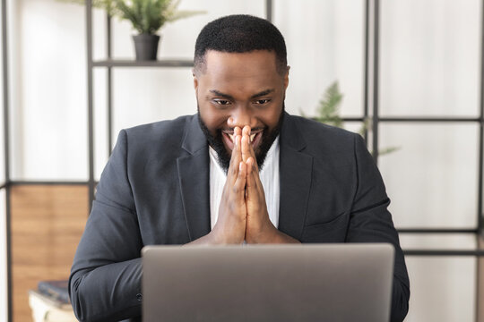 Happy excited business man celebrate his success. African American excited male looking at laptop screen reading good news, satisfied with the result