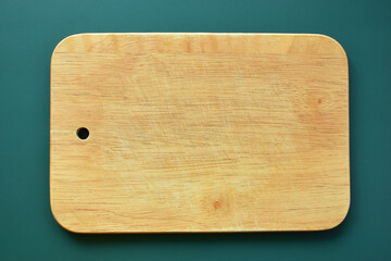 brown wooden cutting board on green background, equipment for cooking in the kitchen
