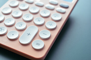 close up modern peach colour pastel calculator and white button on blue background, business and finance accounting concept