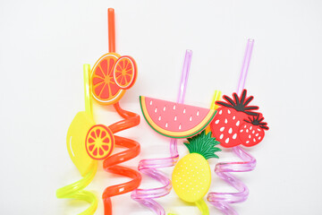 close up colorful fruit drinking staws on white background