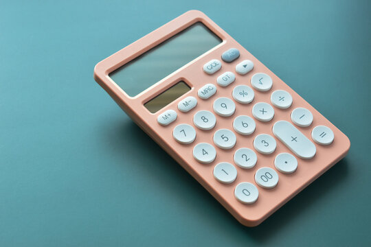 modern peach colour pastel calculator and white button on green background, business and finance accounting concept