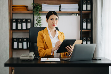 Fototapeta premium Business woman using tablet and laptop for doing math finance on an office desk, tax, report, accounting, statistics, and analytical research concept in office.