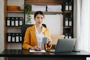 Business woman using tablet and laptop for doing math finance on an office desk, tax, report, accounting, statistics, and analytical research concept in office.