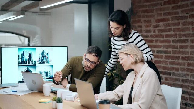 Video of smart group of architects working with laptops and blueprints while talking of their new design business in the office.