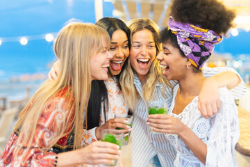 Cheerful girls having fun and toasting mojito at bar on the beach . Summer, holiday and leisure concept