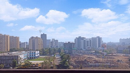 View from an building showing the construction work going on, a nearby school with buses, developments of the city.